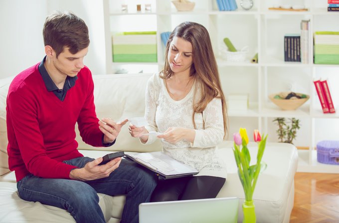 foto van vrouw en man op bank met rekenmachine in hand